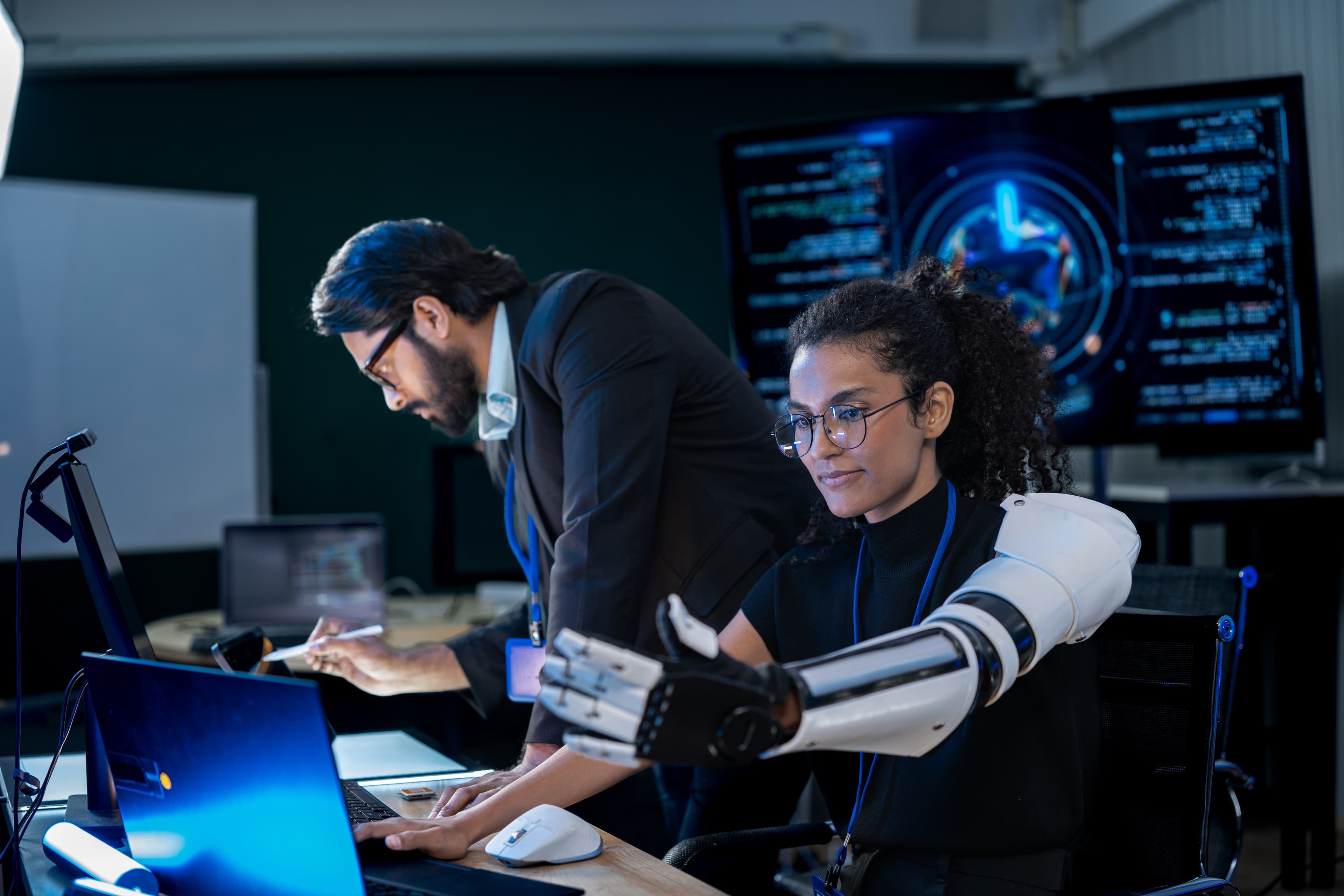 A researcher and an engineer reviewing AI-assisted work on a robotic arm